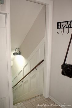 an open door leading to a room with a light on the wall and a coat rack