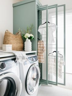 a washer and dryer in a small room with green walls, white flooring and open closet doors