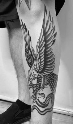 a man's leg with an eagle and snake tattoo on the side of his leg