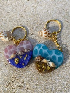 two heart shaped key chains sitting on top of sand