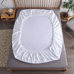 an overhead view of a bed with a white comforter on it and a wooden headboard