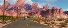 a car is driving down the road in front of some mountains and rock formations,