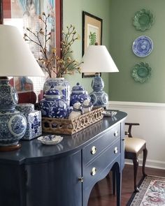 a table with blue and white vases on top of it next to a lamp