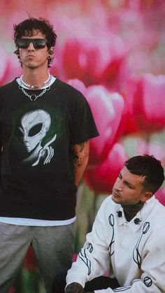 two men sitting next to each other in front of a flower field with pink tulips