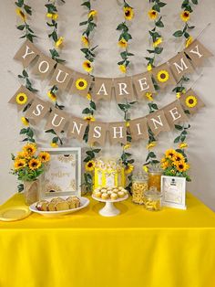 a table topped with sunflowers and cake next to a sign that says you are my sunshine shine