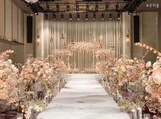 the aisle is lined with tall vases filled with pink flowers and greenery for an elegant wedding ceremony