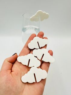 a hand holding four white clouds and a glass of water