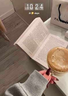 a person is reading a book and holding a cup of coffee