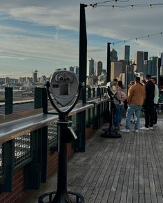 people are standing on the top of a building looking out at the city and water