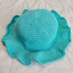 a crocheted blue hat sitting on top of a bed