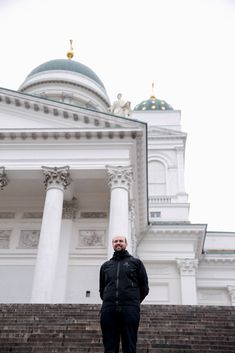 a man standing on steps in front of a large white building with columns and domes