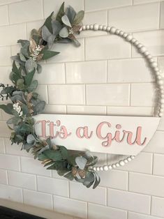 a sign that says it's a girl with flowers and leaves hanging on the wall