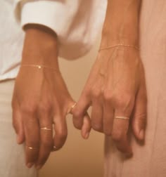 two people holding hands with gold rings on their fingers and one wearing a white shirt