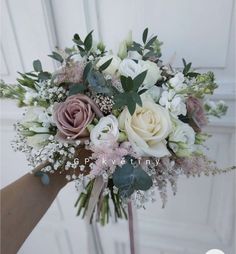 a bridal bouquet with pink, white and green flowers in front of a door