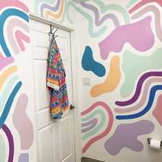 a bathroom decorated with multicolored wallpaper and a towel hanging on the door