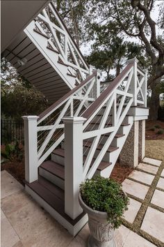 a white stair case next to a potted plant