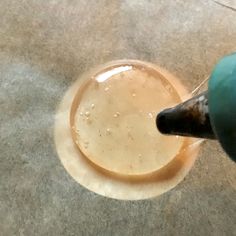 a person pouring liquid into a bowl on the ground with a blue bottle in it