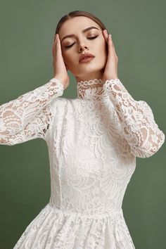 a woman wearing a white lace dress with her hands on her head and eyes closed