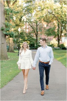 an engaged couple holding hands and walking down a path in the park during their engagement session