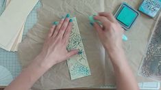 a woman is working on some crafting supplies with her hands and stamp pad in front of them