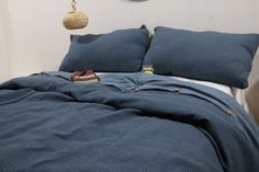 a bed with blue sheets and pillows on top of it next to a wall clock