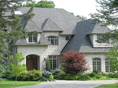 a large white brick house with lots of windows and trees in front of the house