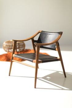 a wooden chair sitting on top of a white floor next to a brown and orange rug