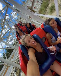 two women sitting on roller coasters at an amusement park with others in the background