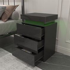 a black night stand with three drawers and a pillow on the floor next to it