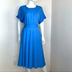 a mannequin dressed in a blue dress with short sleeves and pleaed skirt