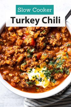 slow cooker turkey chili in a white bowl with a spoon and napkin on the side