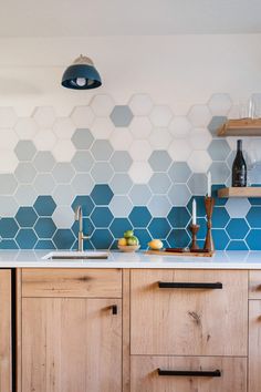 a kitchen with blue hexagonal tiles on the wall and wooden cabinetry in front