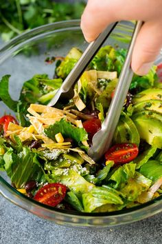 someone is cutting into a salad in a glass bowl