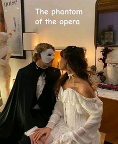 a man and woman sitting next to each other in front of a wall with the words the phantom of the opera on it