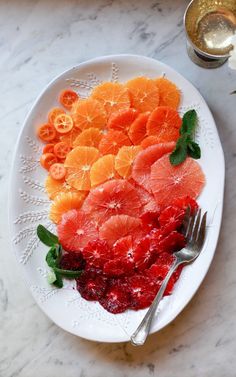 a white plate topped with sliced oranges and cranberry sauce next to a fork