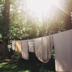 clothes hanging out to dry in the sun on a line with trees and grass behind them