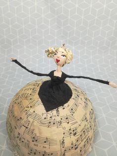 a doll sitting on top of a ball covered in musical notes and music staffs