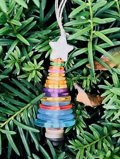 an ornament hanging from a tree filled with colorful beads and leafy branches