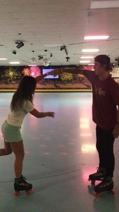 two people on skateboards in an indoor skating rink with lights and fireworks behind them