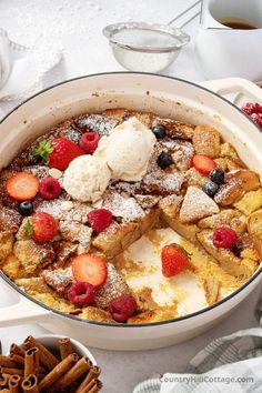 french toast with berries and ice cream in a white casserole dish on a table