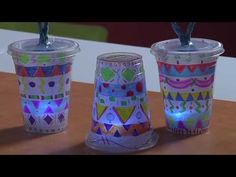 three cups with lights in them sitting on a table next to each other and one has a straw