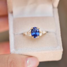 a person holding a ring with a blue and white stone in it's center