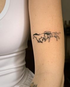 a woman with a tattoo on her arm that has two horses running in the same direction