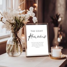 a vase filled with white flowers sitting next to a sign on top of a table