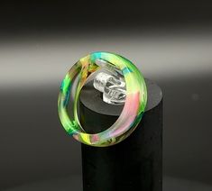 a glass ring sitting on top of a black stand with a skull in the middle