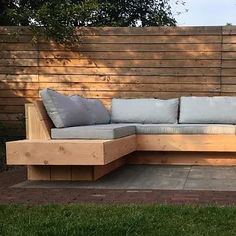 a wooden couch sitting on top of a cement slab in front of a wooden fence