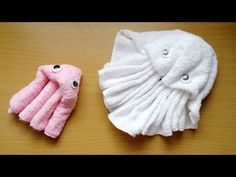 two pink and white towels sitting next to each other on top of a wooden table