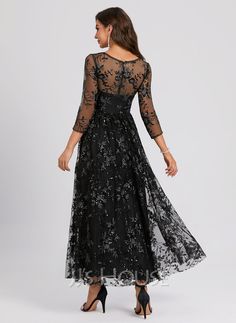 a woman wearing a long black dress with sheer sleeves and floral lace on the top