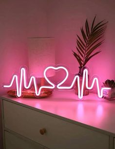 a neon sign that says i love you next to a potted plant on a dresser