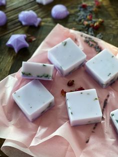 five soap bars sitting on top of a piece of wax paper next to some flowers